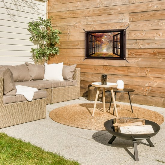 Une affiche de jardin avec une fenêtre ouverte sur une forêt d'automne est accrochée à une clôture en bois sur une terrasse.
