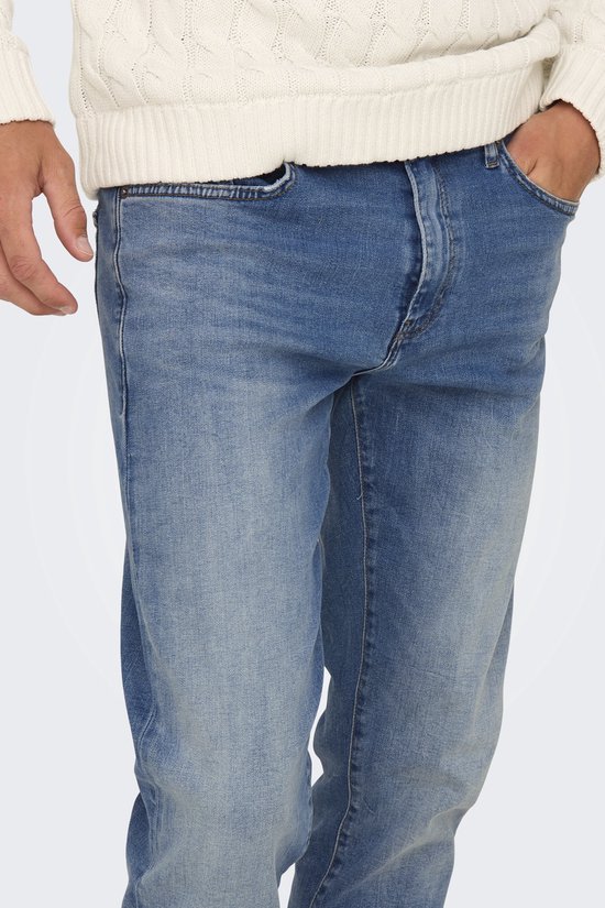Detail van blauwe jeans, met een hand in de zak.