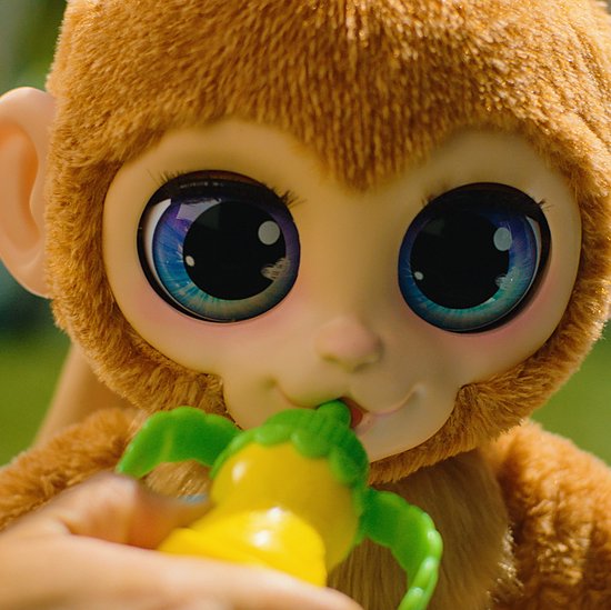 Close-up van een bruine FurReal Peanut aap die aan een gele drinkfles sabbelt.