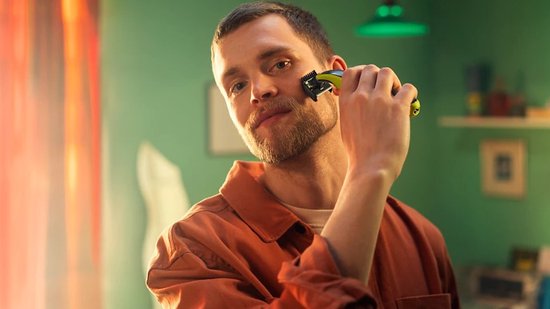 Man met baard trimt zijn wang met een groene en zwarte Philips OneBlade.