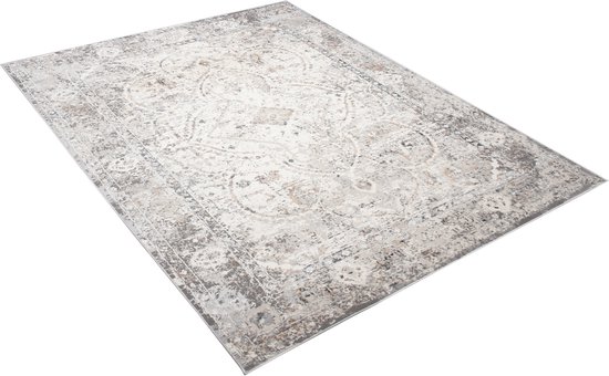 Un tapis beige avec un motif oriental délavé, posé sur un fond blanc.