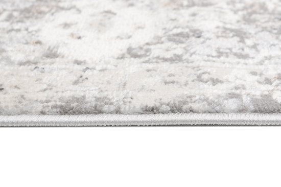 Détail du bord d'un tapis vintage beige clair avec motif détaillé.