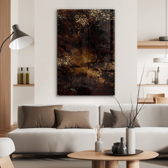 Abstract glas-in-lood schilderij in bruin en zwart met gouden spikkels, hangend boven een bank.