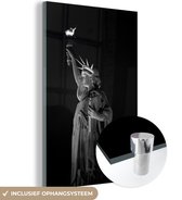 MuchoWow® Glasschilderij 80x120 cm - Schilderij acrylglas - Verlicht Vrijheidsbeeld in de nacht in New York Amerika - zwart wit - Foto op glas - Schilderijen
