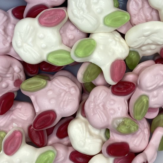 Een close-up van veel snoepjes in de vorm van lammetjes in wit, roze en met groene en rode accenten.