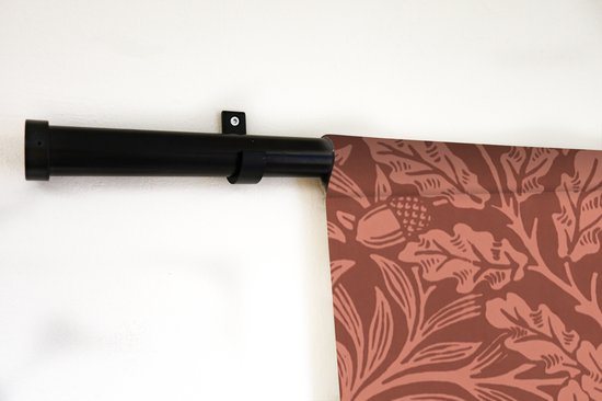 Detail van bruin wandkleed met bladeren en eikels patroon, aan zwarte roede.