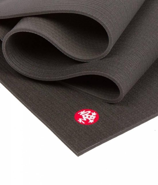 Zwarte Manduka yogamat, deels opgerold, met rood logo.