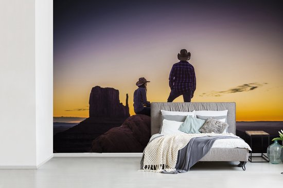 Deux cowboys dans une zone de montagne au coucher du soleil fotobehang
