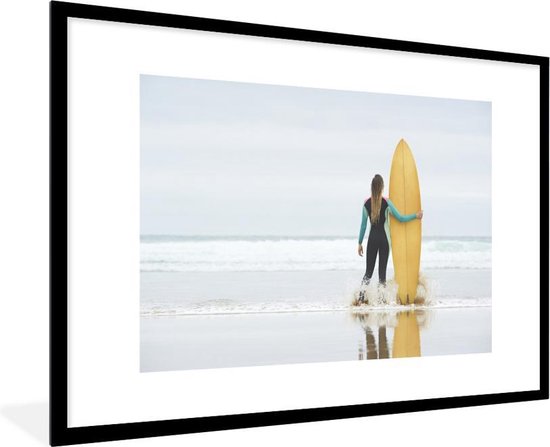 Fotolijst incl. Poster - Vrouwelijke surfer staat naast surfplank - 120x80 cm - Posterlijst