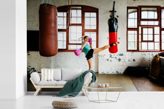 Foto: Behang fotobehang een thaise bokser doet een high kick in een fitnessruimte breedte 450 cm x hoogte 300 cm