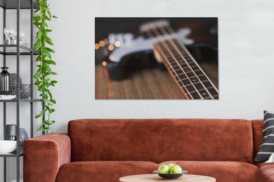 Une guitare basse repose sur une table Toile 140x90 cm - Tirage photo sur toile (Décoration murale salon / chambre)