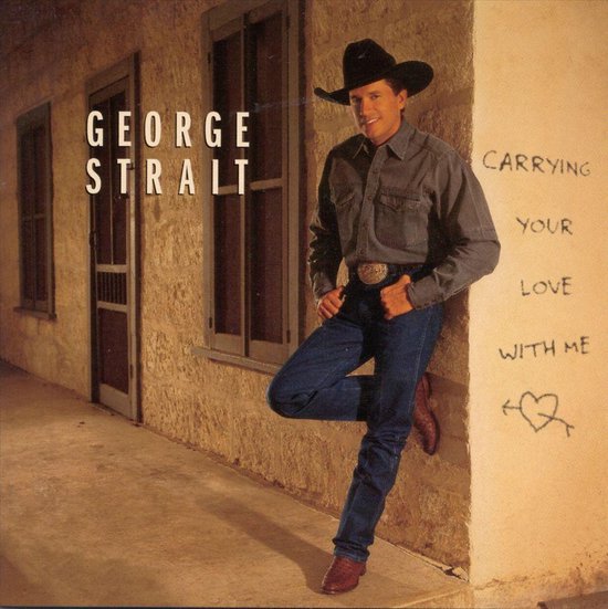 George Strait in een grijs denim hemd, blauwe jeans, zwarte cowboyhoed en bruine laarzen leunt tegen een muur met de tekst 'Carrying Your Love With Me'.