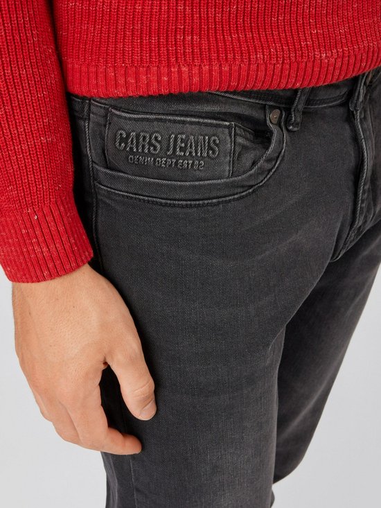 Detail van een spijkerbroek met opgedrukt logo 'CARS JEANS DENIM DEPT EST 02' op de zak.