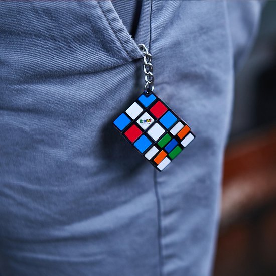 Rubik's Cube sleutelhanger met veelkleurige vlakken, hangend aan een grijze broek.