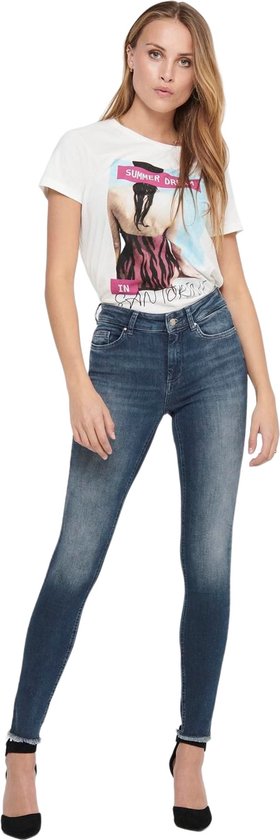 Vrouw met een witte t-shirt met print en een donkerblauwe skinny jeans met rafelige zoom.