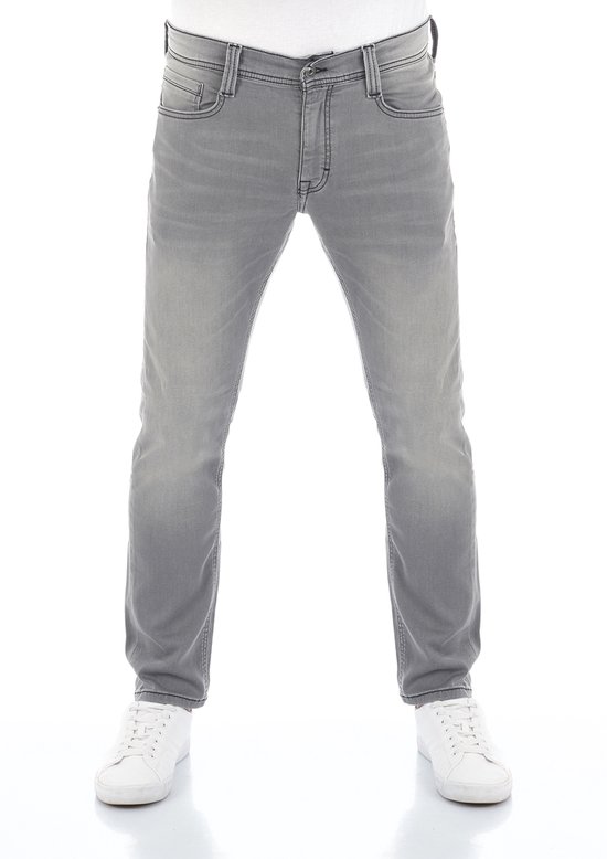 Model draagt een grijze tapered fit jeans met witte sneakers, gezien vanaf de voorkant.