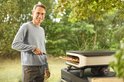Man met bril haalt een pizza uit de Cozze pizzamaker.