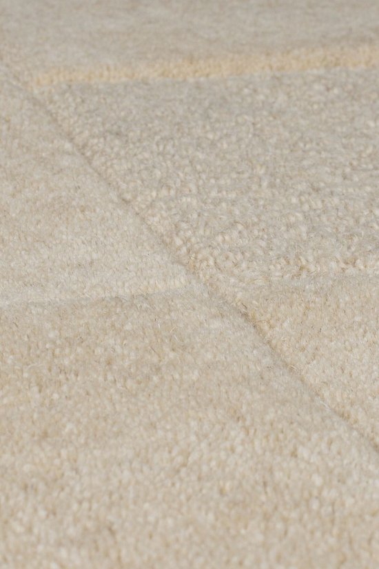 Close-up van de textuur van een naturelkleurig vloerkleed met blokpatroon.