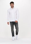 Man met wit overhemd en grijze jeans.