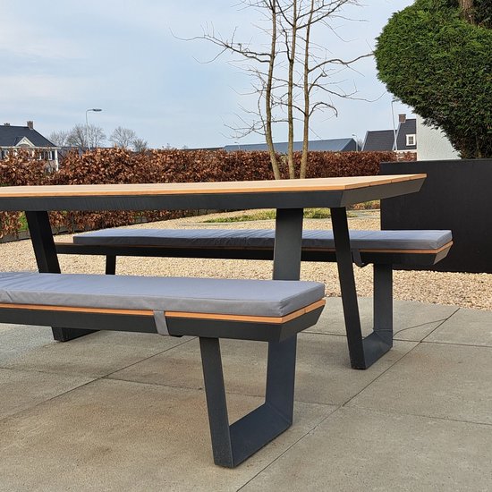 Picknicktafel met grijze bankkussens en houten elementen.