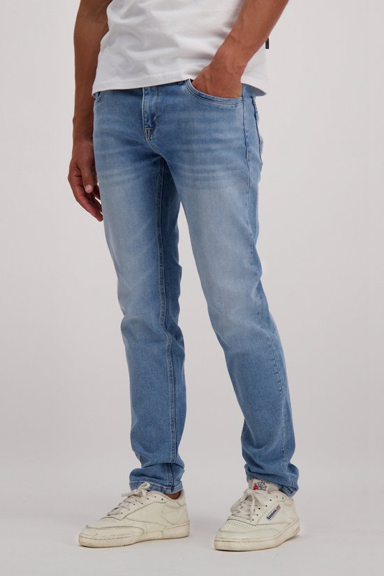 Man met lichtblauwe jeans, slim fit, zichtbaar van de zijkant, met lichte verouderde plekken.