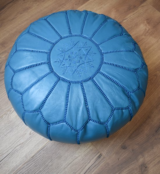 Turkooizen, ronde poef met stermotief geborduurd op het bovenste deel, staand op een houten vloer.
