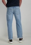 Man in donkerblauw T-shirt en lichtblauwe jeans met opgerolde pijpen en witte sneakers, van achteren gezien.