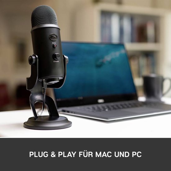 Microphone Yeti noir sur un bureau à côté d'un ordinateur portable avec un écran bleu.
