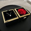 Zwarte juwelendoos met gouden rand, een rode roos en een zilveren ketting met zirkonia steen.