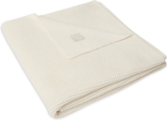 Couverture de lit en maille crème pliée avec une étiquette.