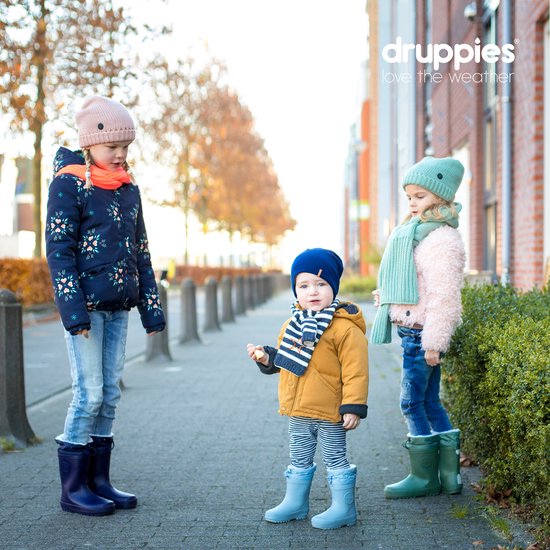 Drie kinderen staan op een straat. Het linker kind draagt een blauwe jas, het middelste kind een gele jas en het rechter kind een roze jas.