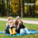 Twee meisjes met laarzen, zittend op een deken in het bos met herfstkleuren.