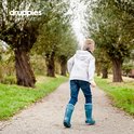 Jongen loopt op een pad, draagt petrolblauwe regenlaarzen met witte voering.