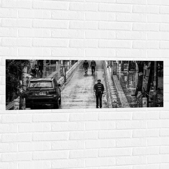 WallClassics - Muursticker - Man wandeldn door Dorpje (zwart/wit) - 120x40 cm Foto op Muursticker