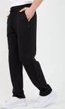 Man in zwarte joggingbroek met trekkoord en witte sneakers, zijaanzicht.
