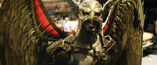 Aldis Hodge als Hawkman met gouden vleugels en een masker, met een glimlach.