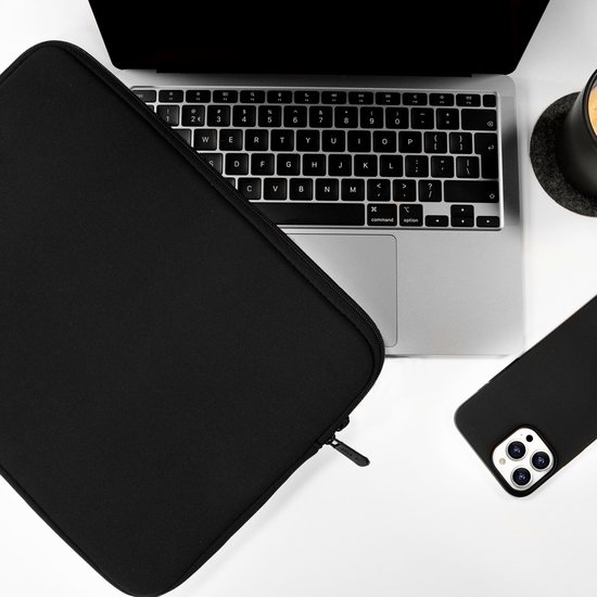 Zwarte laptophoes naast een laptop, telefoon en mok