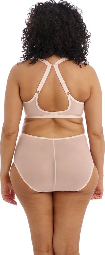 Achterkant van model in lichtroze beha en slip met stippen en kanten details.