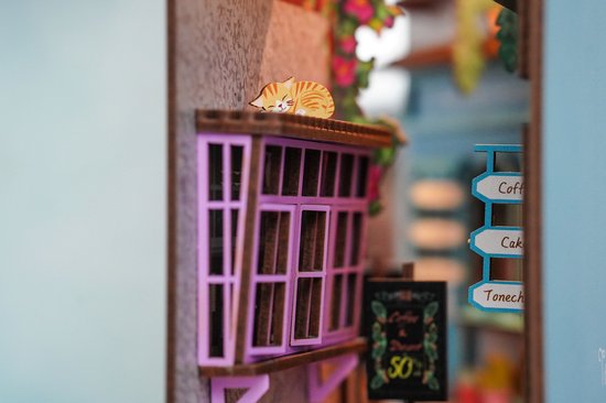 Een slapende miniatuurkat op een paarse vensterbank van het 'Island of Love' café-model.