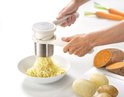Witte Helix aardappelpers in gebruik, die aardappelen tot slierten perst in een witte kom.
