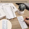 Wit planbord met takenlijst, waarop iemand een taak aanstreept. Naast een cactus in pot.