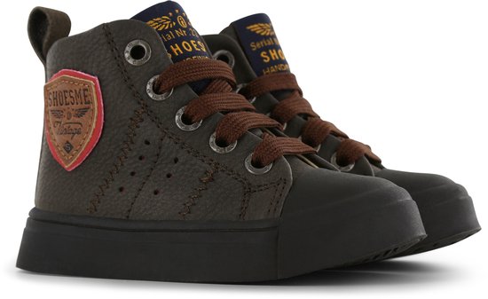 Twee donkerbruine leren hoge sneakers naast elkaar met veters, ritsen en logo's.