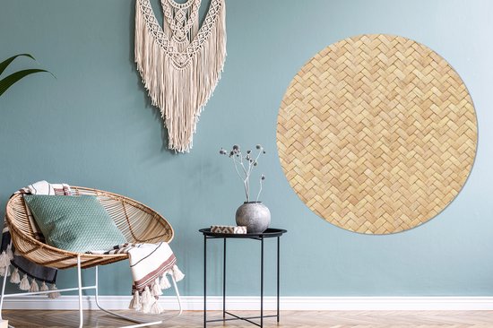 Décoration murale ronde en rotin avec motif tressé, à côté d'une chaise en rotin et d'une tenture murale en macramé.