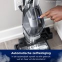 Een hand drukt op de blauwe aan/uit-knop van de Bissell CrossWave. De tekst 'Automatische zelfreiniging' staat onderaan.