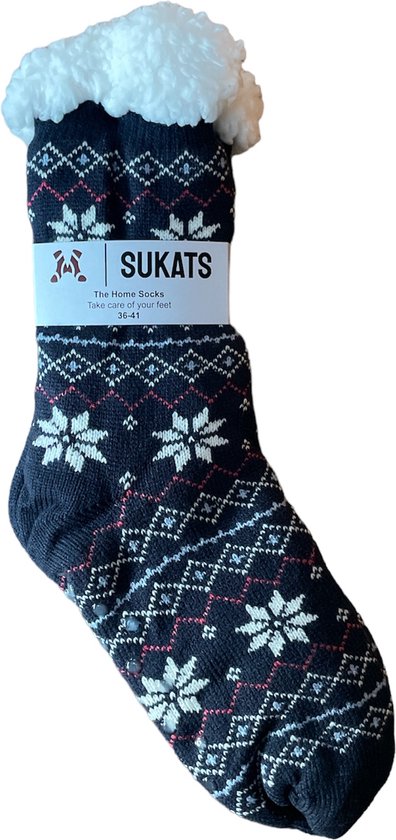 Donkerblauwe Sukats huissok met fair isle patroon van witte sneeuwvlokken en rode ruitjes. De sok heeft een witte fluffy boord en een pakpapier met Sukats logo en tekst.