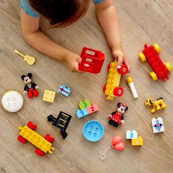 Kind speelt met LEGO DUPLO Mickey & Minnie verjaardagstrein onderdelen: Mickey, Minnie, Pluto, cadeautjes, blokken en een gitaar.