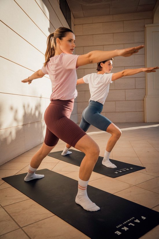 Twee vrouwen doen yoga in een blauwe en bordeauxrode nauwsluitende sportlegging.