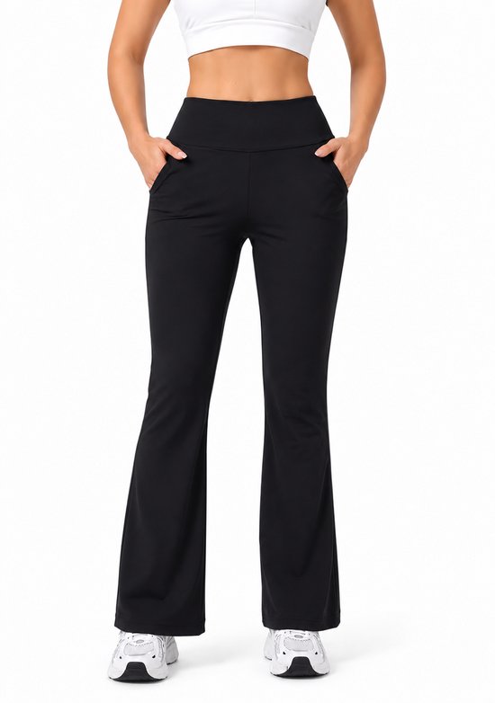 Model van voren met zwarte flare broek met hoge taille en zakken, en witte sportschoenen.