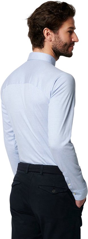 Homme portant une chemise en jersey bleu clair, mains dans les poches, vu de dos