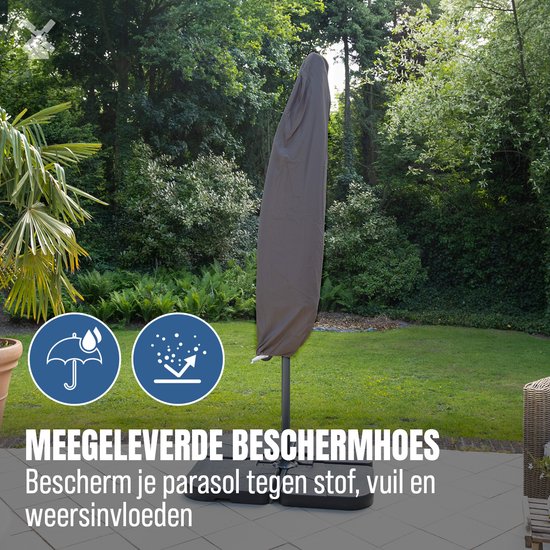 Grijze zweefparasol in een bruine beschermhoes, op een terras met groen.
